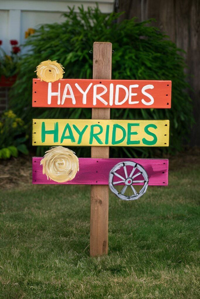 A sign made from pallet wood that says 'Hayrides,' painted in bright colors with hay bales and wagon wheel decorations, placed in a yard