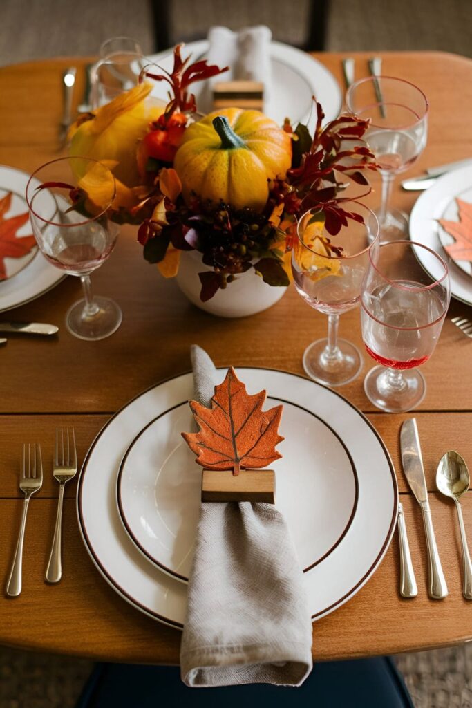 Leaf-shaped wooden napkin rings painted in fall hues, attached to wood or metal strips for a seasonal dining table