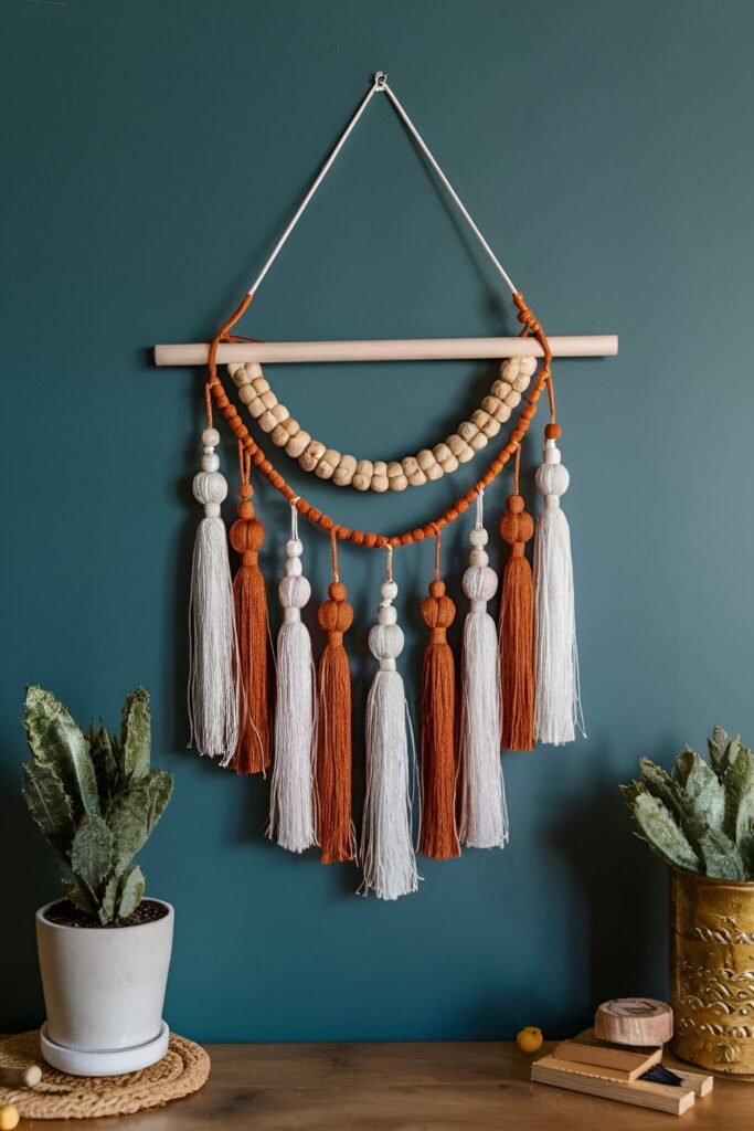 Wall hanging combining wood and fabric in fall colors, adorned with tassels and beads for a boho-chic look