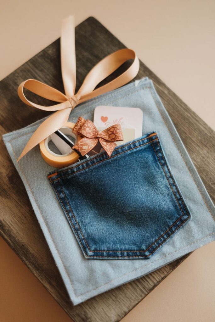 A fabric square with a denim pocket, holding a small gift wrapped with ribbon for a unique and eco-friendly presentation