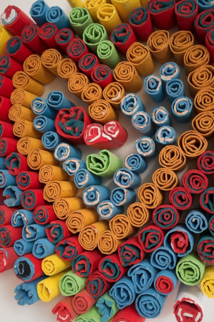 Cardboard spirals tightly rolled and arranged into a pattern, painted in vibrant colors for a playful and dynamic wall decoration