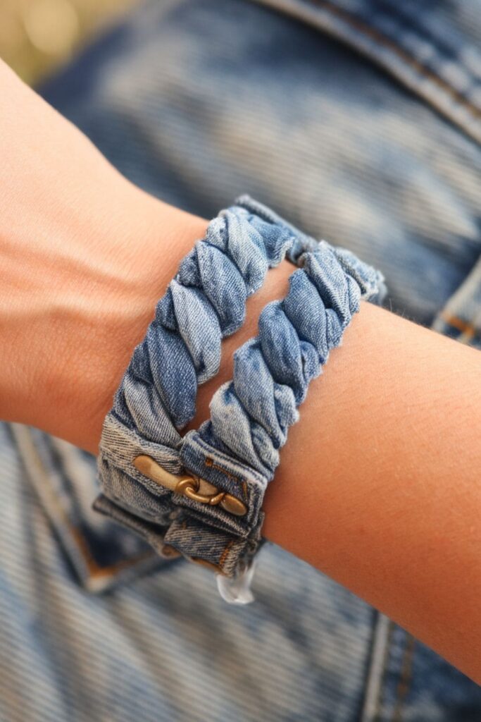 Casual denim bracelet made from braided denim strips with clasps at each end, styled as a laid-back accessory