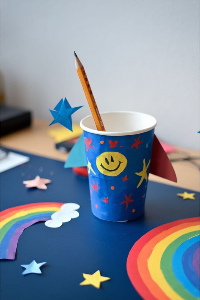 Colorful paper cups turned into rocket cones attached to pencils, displayed as playful desk decorations