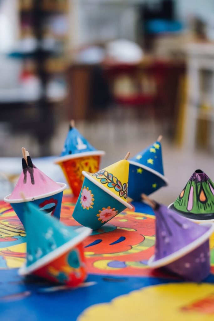 DIY spinning tops made from paper cups with colorful designs, spinning on a flat surface with pencils or toothpicks as centers