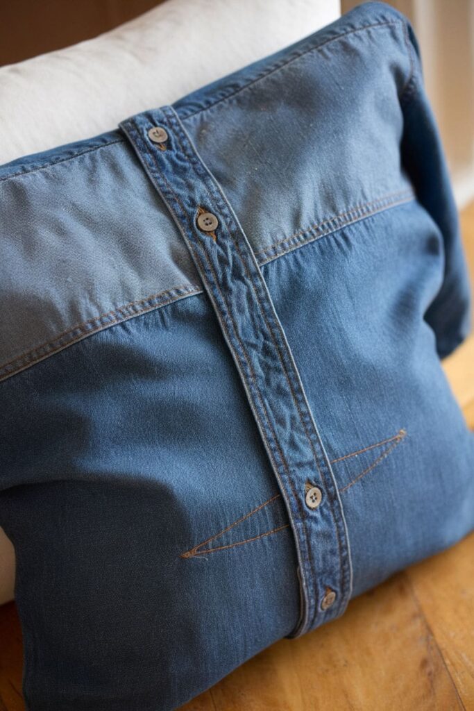 Upcycled denim shirt used as a pillow cover, with the button placket in the center for a no-sew and unique closure