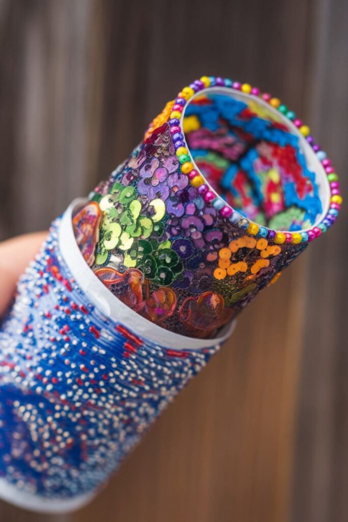 A colorful kaleidoscope made from a paper towel roll filled with beads and sequins, held up to light to reveal beautiful patterns