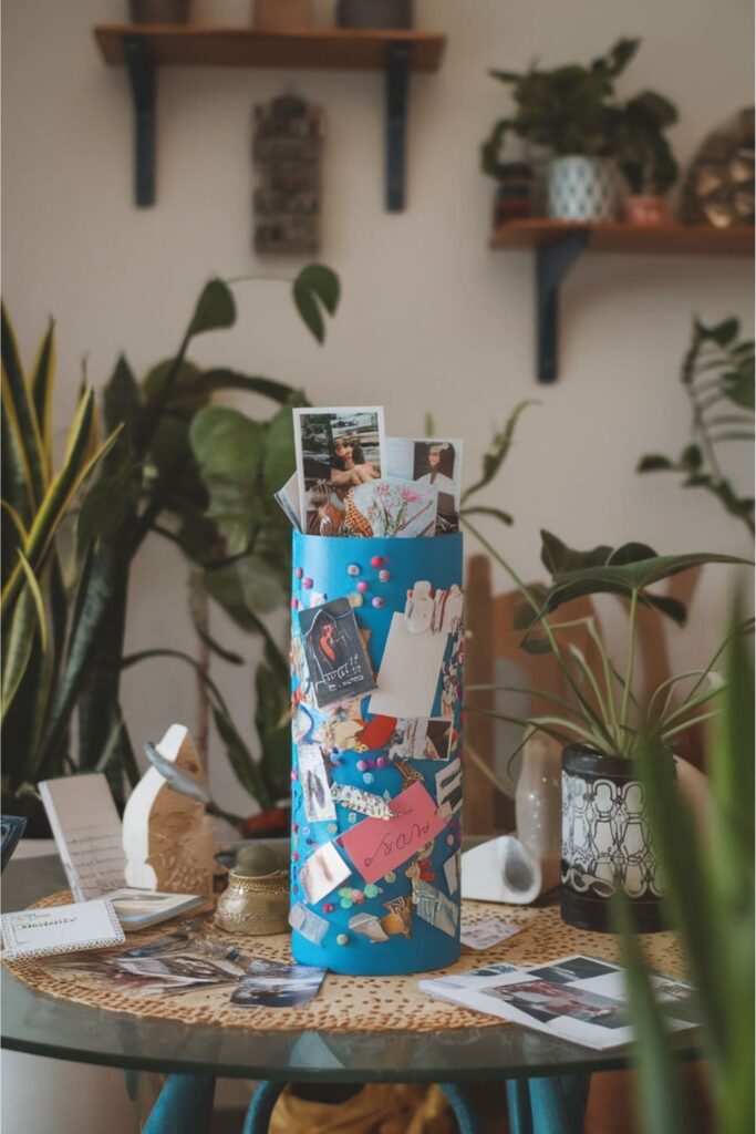 Colorful cardboard roll decorated as a memory time capsule, filled with photos, notes, and keepsakes on a table