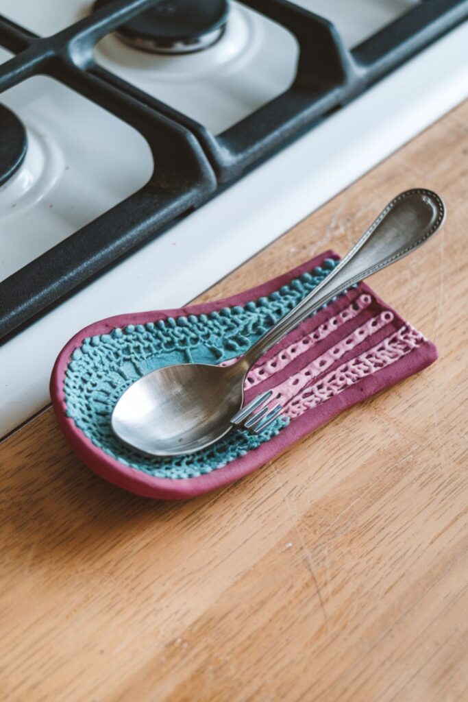 Curved clay spoon rest with textured patterns and vibrant colors