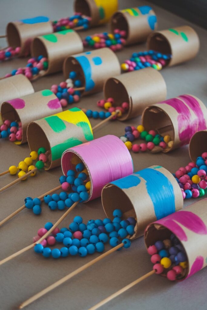 DIY percussion instruments made from cardboard rolls, with balloon-covered ends and colorful designs, sitting on a craft table