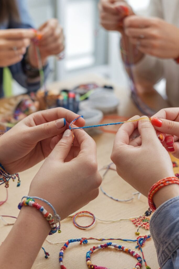 Friends making friendship bracelets with colorful threads and beads