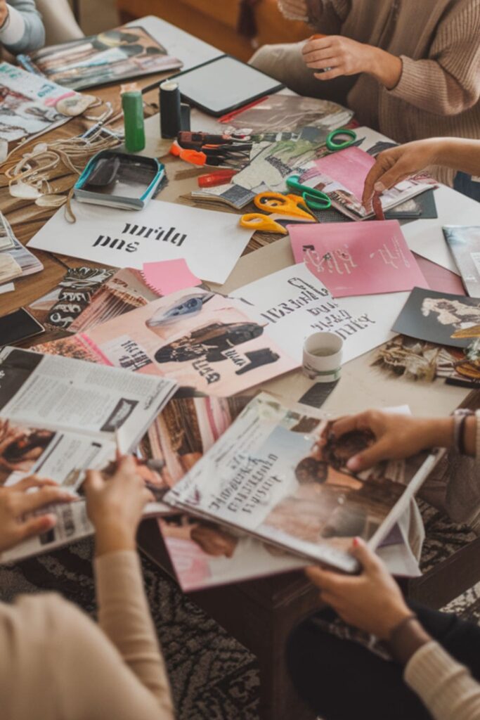 Friends making vision boards with magazines and photos on a table