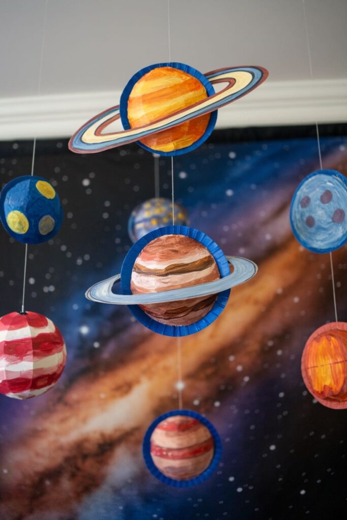 Paper plates painted as planets from the solar system, including Saturn's rings and Jupiter's spots, hanging as a mobile