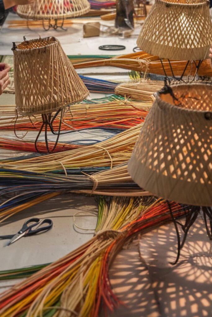 People weaving reed around frames to create unique lampshades