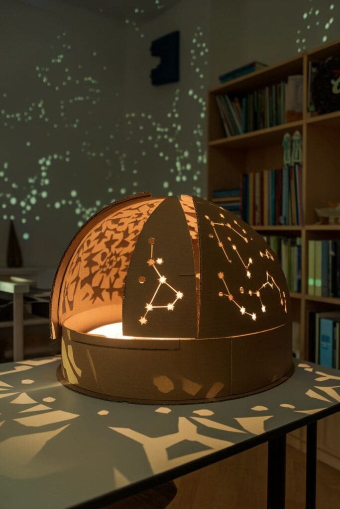 Cardboard dome with star patterns lit by LEDs on a study table