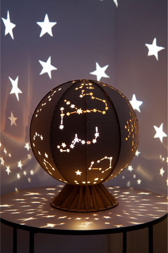 Cardboard globe with star cutouts lit by LEDs on a table