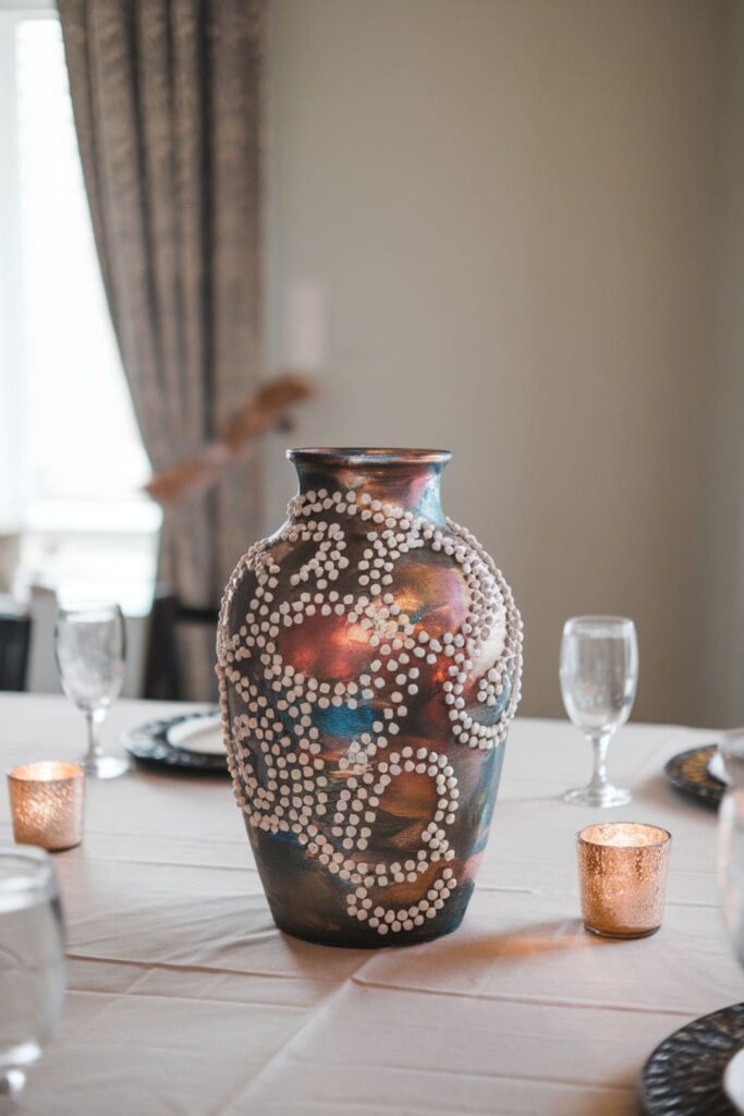 Decorative hot glue vase with metallic patterns on a table